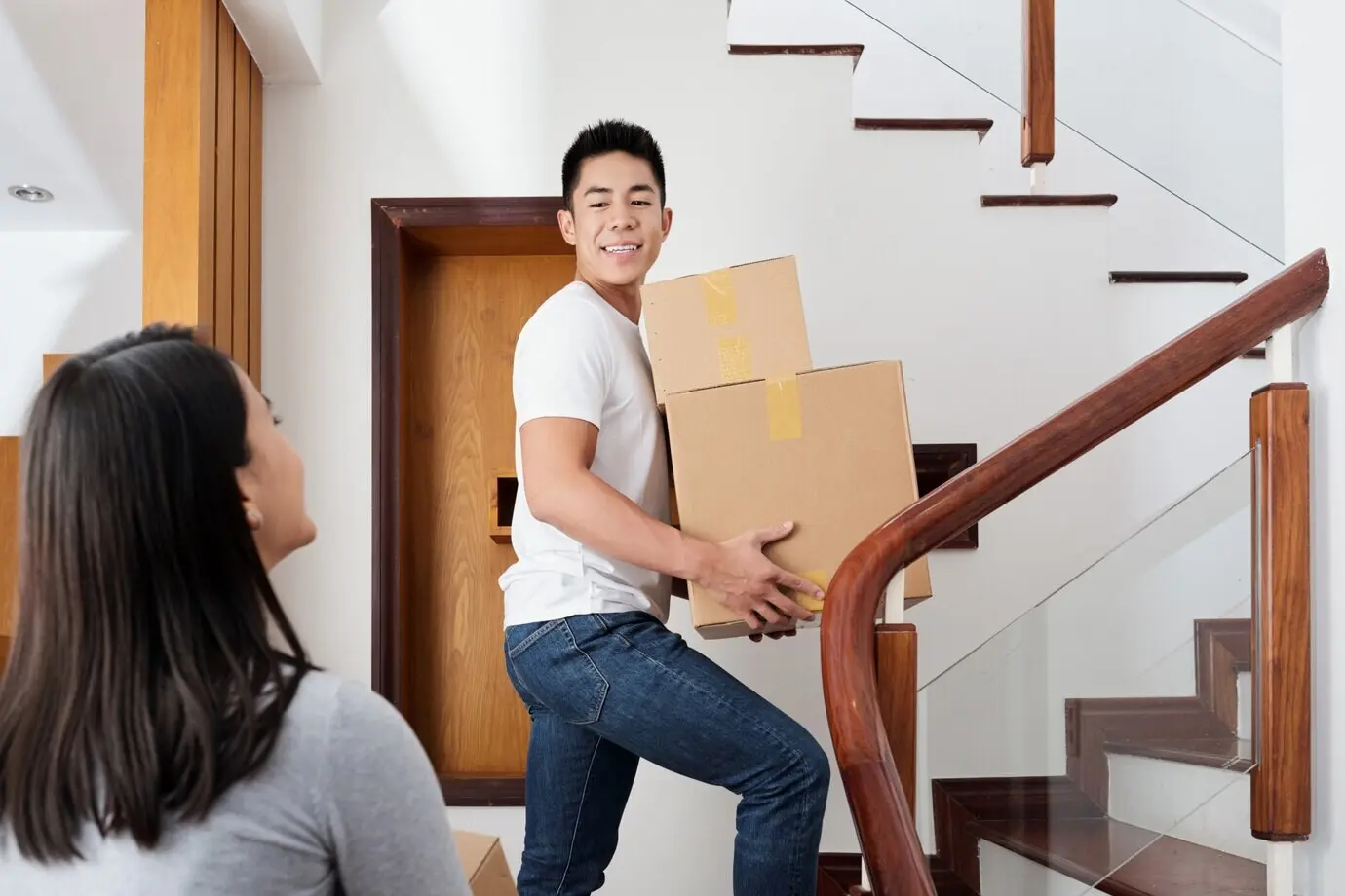 A young interracial couple bringing cardboard boxes to their new apartment.