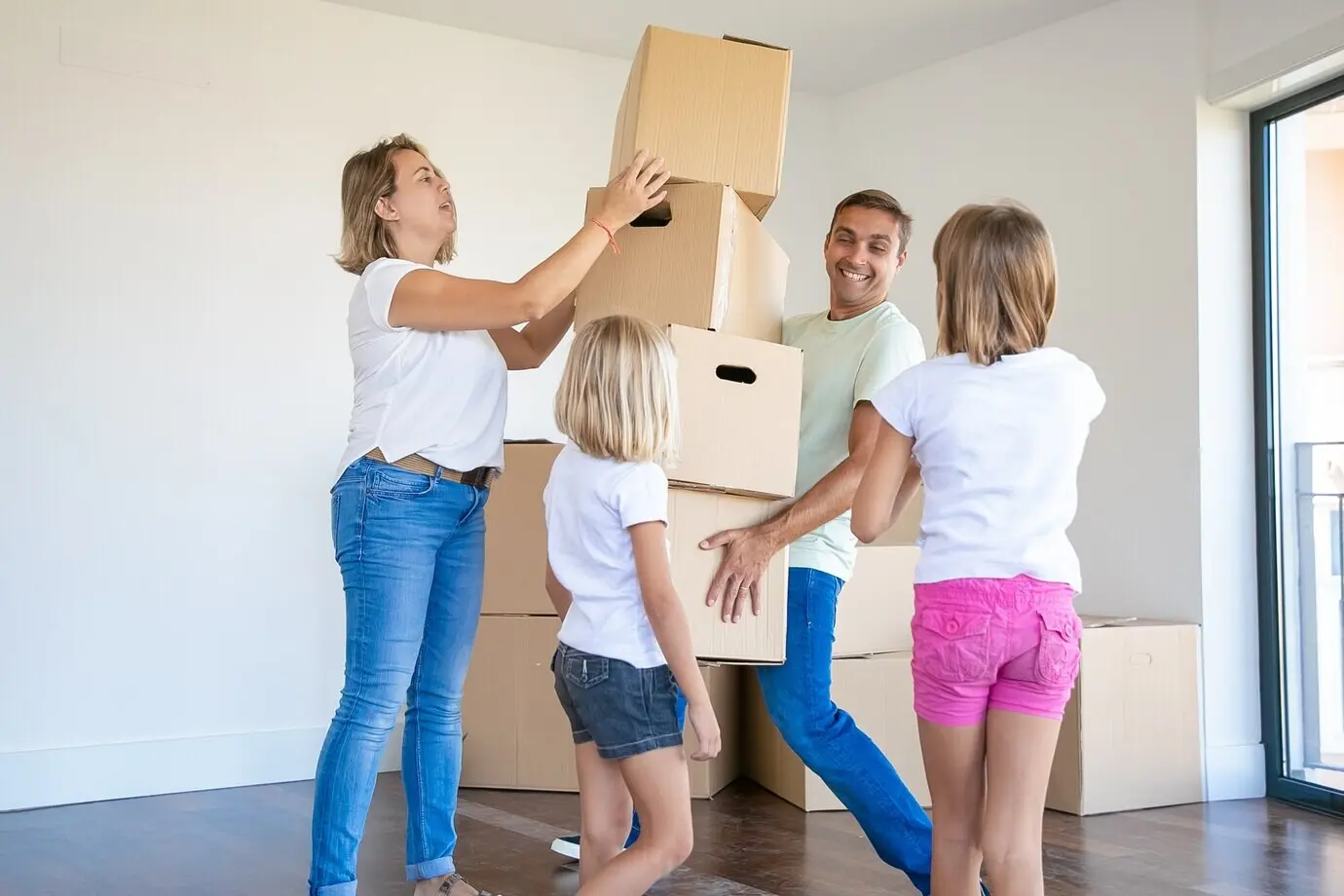 A good-looking father smiles while holding a stack of boxes.